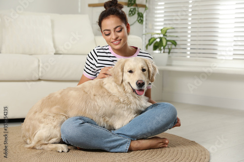 Young woman and her Golden Retriever at home. Adorable pet
