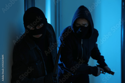 Dangerous criminals with gun and crow bar in hallway © New Africa