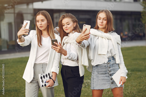 Students in a park. Girls on a campus. Friends with a phone.