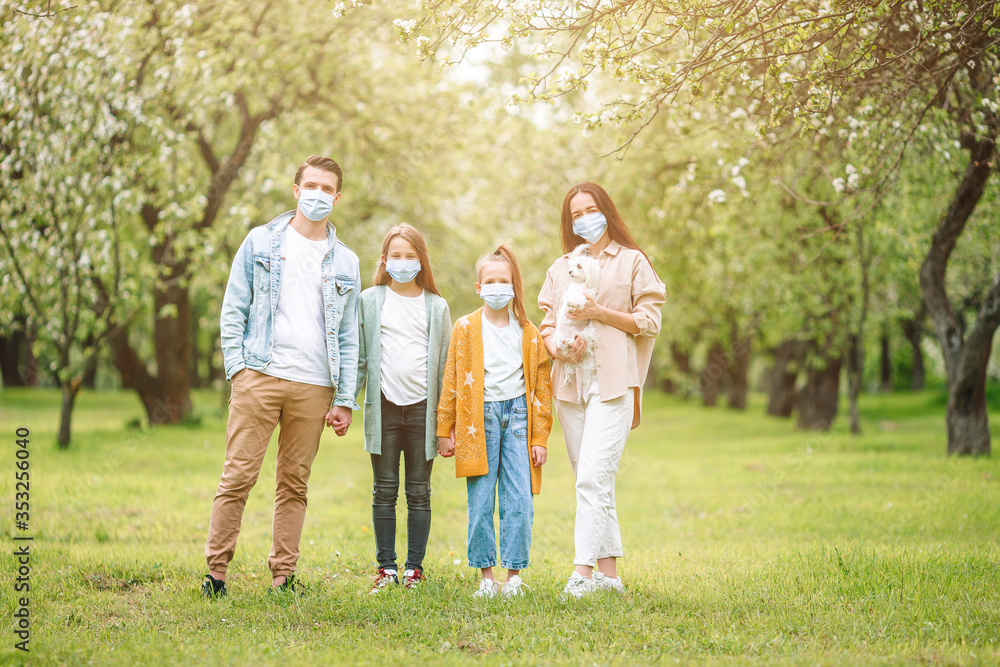 Fototapeta premium Adorable family in blooming cherry garden in masks