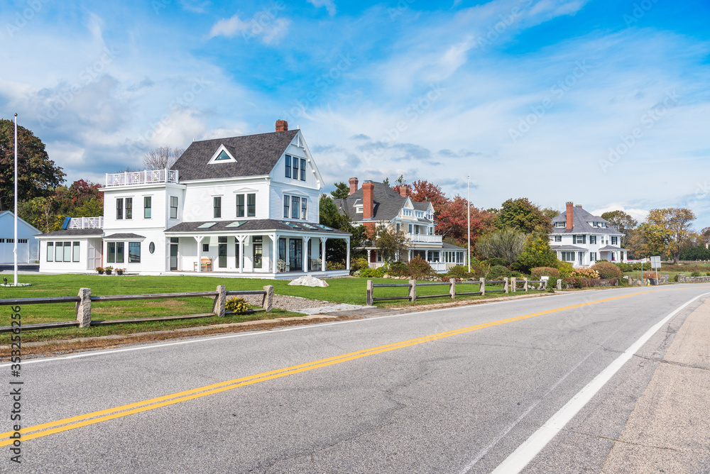 Deserted stretch of a coast road lined with beautiful detached houses on a clear autumn day. New England, USA.