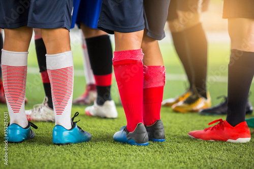 boy soccer players are put multi color sport shoes and standing on green artificial turf with coach before training and start game.