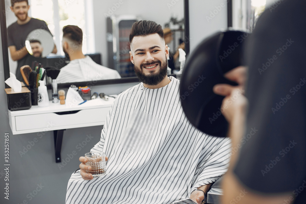 Fototapeta premium Man with a beard. Hairdresser with a client. Guy drinkig a whiskey