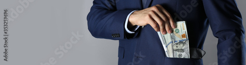 Man putting bribe into pocket on grey background, closeup with space for text. Banner design