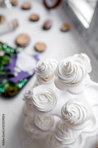Cupcakes with white cream. Morning of the bride. Sweets and cakes are in candy bar for the wedding ceremony. Selective focus.