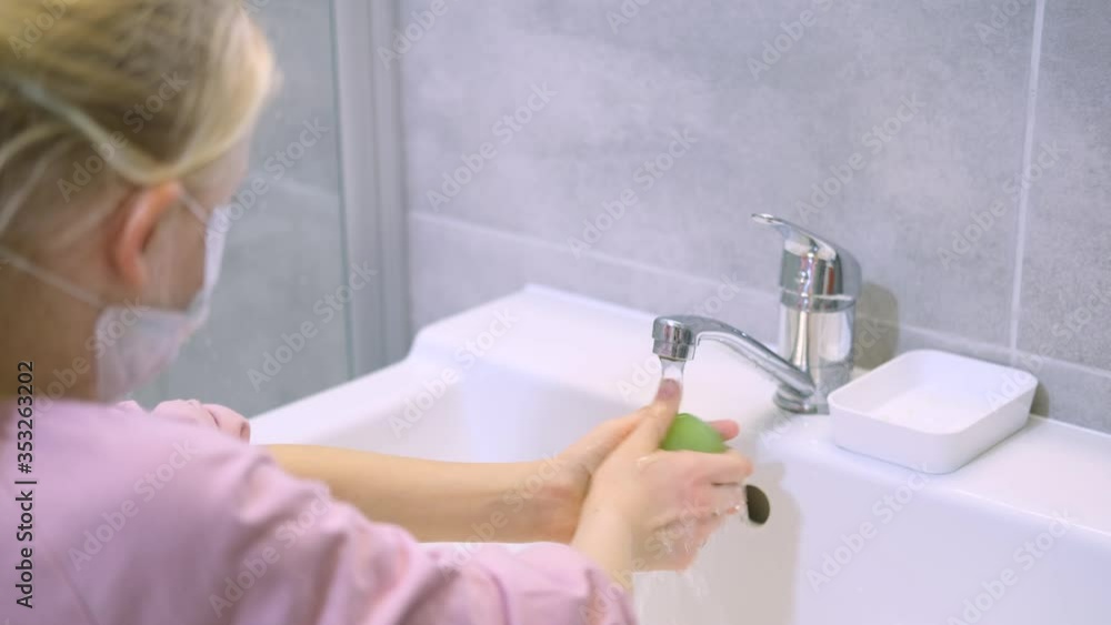 Child blonde girl in medical mask washing hands with green soap in modern bathroom. Cleaning, hygiene and prevention. 4k footage. Child blonde girl in medical mask washing hands with green soap in modern bathroom. Cleaning, hygiene and prevention. 4k footage.
