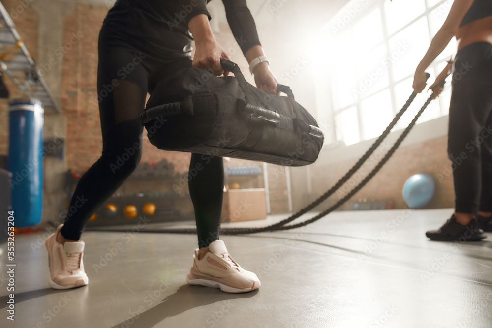 Defeat your weakness. Cropped shot of sportive woman lifting a heavy sandbag while having