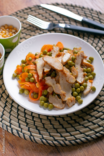 roasted chicken meat with pea and carrot garnish - closeup