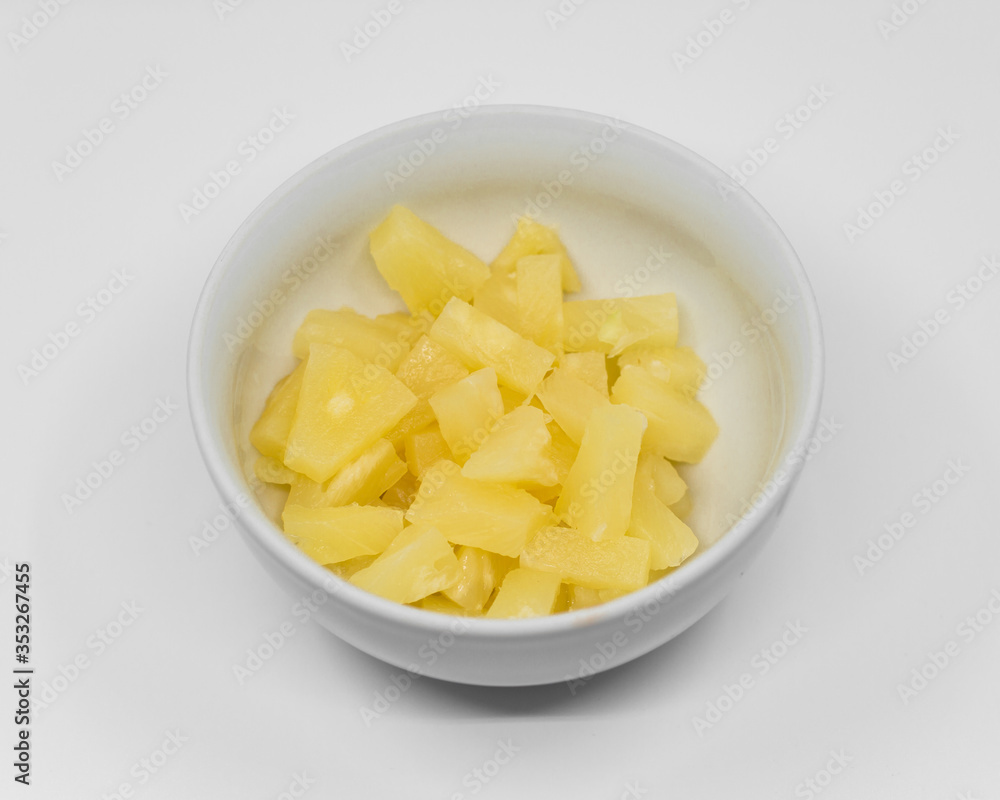 chopped canned pineapple in a white porcelain bowl on a white background chopped canned pineapple in a white porcelain bowl on a white background