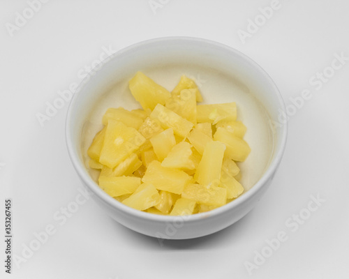 chopped canned pineapple in a white porcelain bowl on a white background