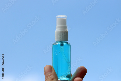 Hand holding Alcohol based hand sanitizer spray on blue sky background. Concept about new normal,social distancing,business, and travel guideline for prevention of Covid-19 (Coronavirus).