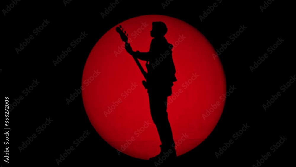 Shadow from an unrecognizable guitarist in a round beam of red light Shadow from an unrecognizable guitarist in a round beam of red light