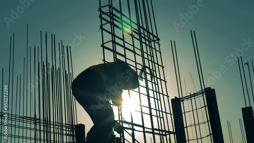 Construction worker works with armature on sunset background. photo