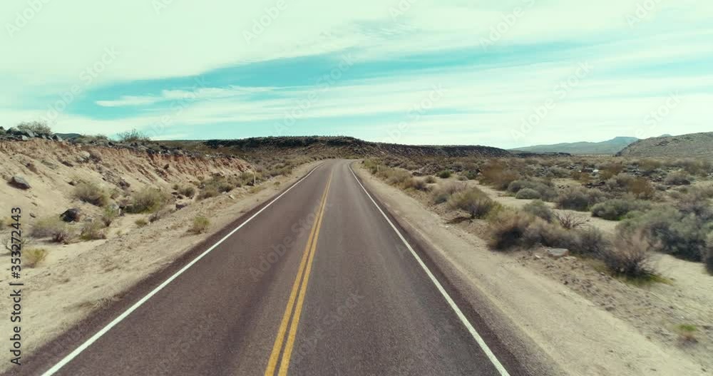 AERIAL - A man walks alone on the middle of the road in the desert on a sunny day while the camera rises and shows a landscape view from the sky AERIAL - A man walks alone on the middle of the road in the desert on a sunny day while the camera rises and shows a landscape view from the sky