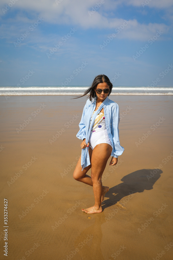 The Atlantic Ocean. Beautiful young girl in a white swimsuit and blue shirt on the ocean.