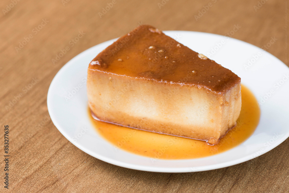 un rico budin bañado con salsa de caramelo en un plato blanco un rico budin bañado con salsa de caramelo en un plato blanco