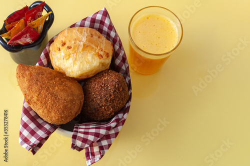 delicious brazilian snacks and fresh juice on a yellow table viewing from above