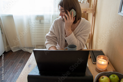 woman talking on the phone while working at a computer at home