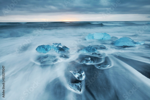 Long exposure of ocean waves and glacial ice chunks on a black sand beach  near Jokulsarlon Glacier Lagoon in southeastern Iceland
