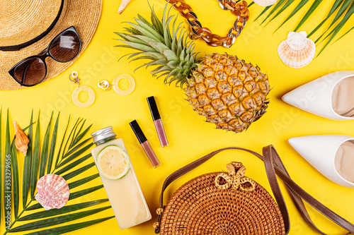 Summer composition with female fashion outfit. Fresh pineapple, hat, tropical palm leaves, straw hat, bamboo bag, shoes on yellow background. Flat lay, top view, overhead, mockup, template