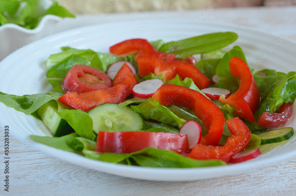 Healthy food. The concept of vegetarian food. Fresh vegetable salad with radish slices, red bell pepper, cherry tomatoes, cucumbers and lettuce leaves top view. Summer fresh salad Healthy food. The concept of vegetarian food. Fresh vegetable salad with radish slices, red bell pepper, cherry tomatoes, cucumbers and lettuce leaves top view. Summer fresh salad