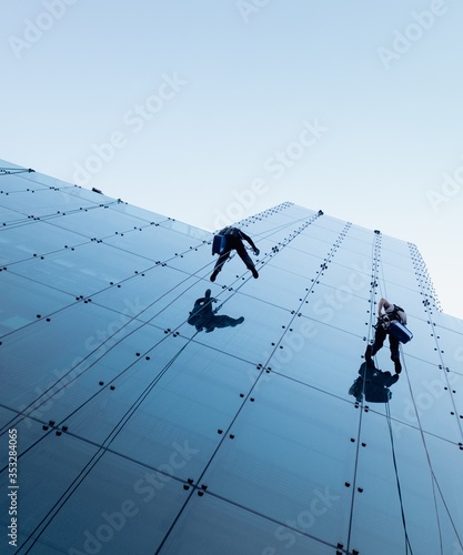 Foto Low angle shot of two persons rappelling at the side of a tall building