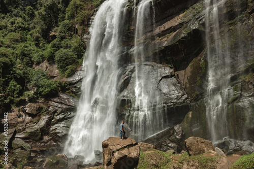 Man walking against the big waterfall in Sri Lanka. Explore the world's beauty and wildlife. Man on a Great waterfall photo