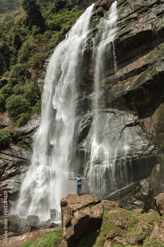 An athletic man is screaming under a beautiful waterfall in rain forest Sri Lanka. Sri Lanka  Bomburu lla waterfall. Travel concept