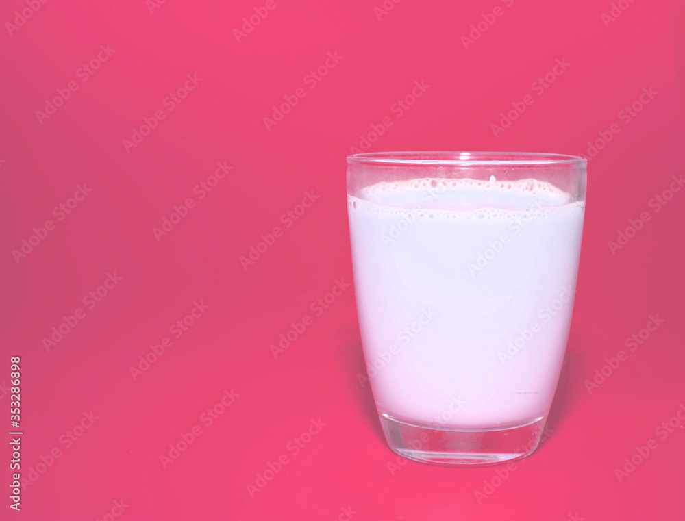 white milk in clear glass on pink background white milk in clear glass on pink background