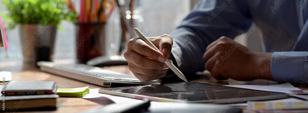 Close up view of graphic designer drawing on digital tablet on wooden worktable Close up view of graphic designer drawing on digital tablet on wooden worktable