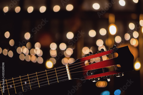 Close-up of acoustic classical guitar with bokeh light background.
