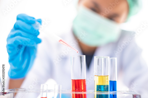  Female researchers are experimenting with pipette dropping a sample into a test tube in an experiment research in laboratory.