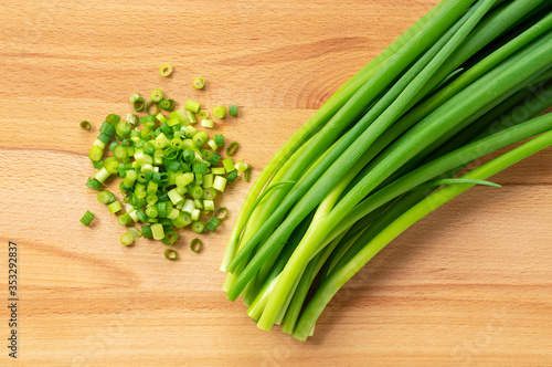 Chopped green onions placed on a wooden board.