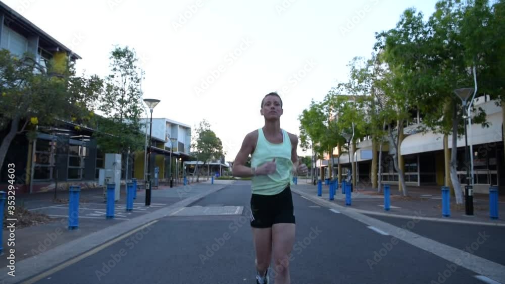 Frontal view of a woman jogging in an empty street. Frontal view of a woman jogging in an empty street.