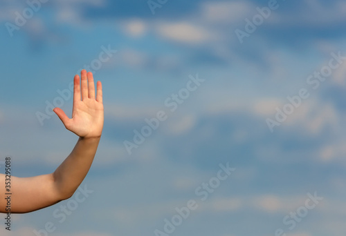 Woman hand over clouds blurred background doing the stop gesture