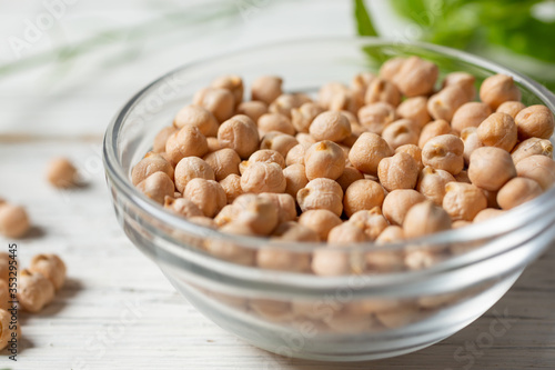 A closeup view of a glass bowl filled with dried chickpeas.