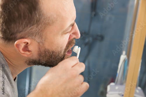 Man brushing his teeth in bathroom