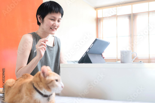 Asian woman work at home online with computer drink coffee and together with cat,happiness concept