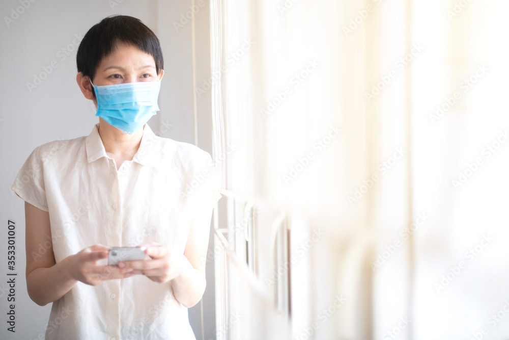 Asian woman wear surgical mask using smart phone for communication feeling worry about news during quarantine time prevent from corona virus or covid-19. Work from home concept.