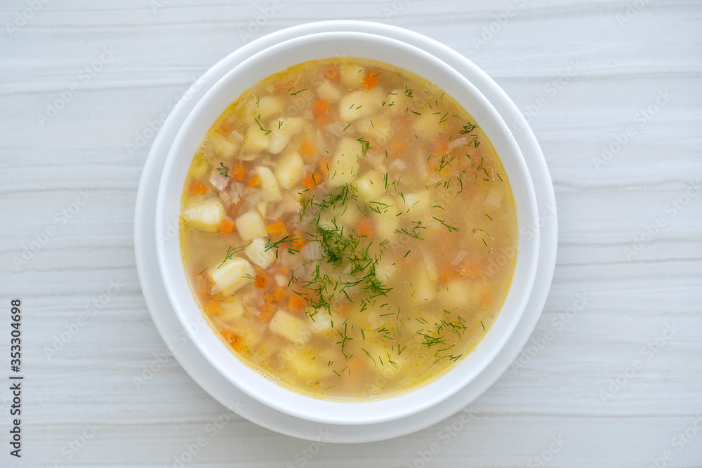 Fresh fish soup with carrots, potatoes and onions in a white plate, close up. Tasty dinner consists of a fish soup with tuna Fresh fish soup with carrots, potatoes and onions in a white plate, close up. Tasty dinner consists of a fish soup with tuna
