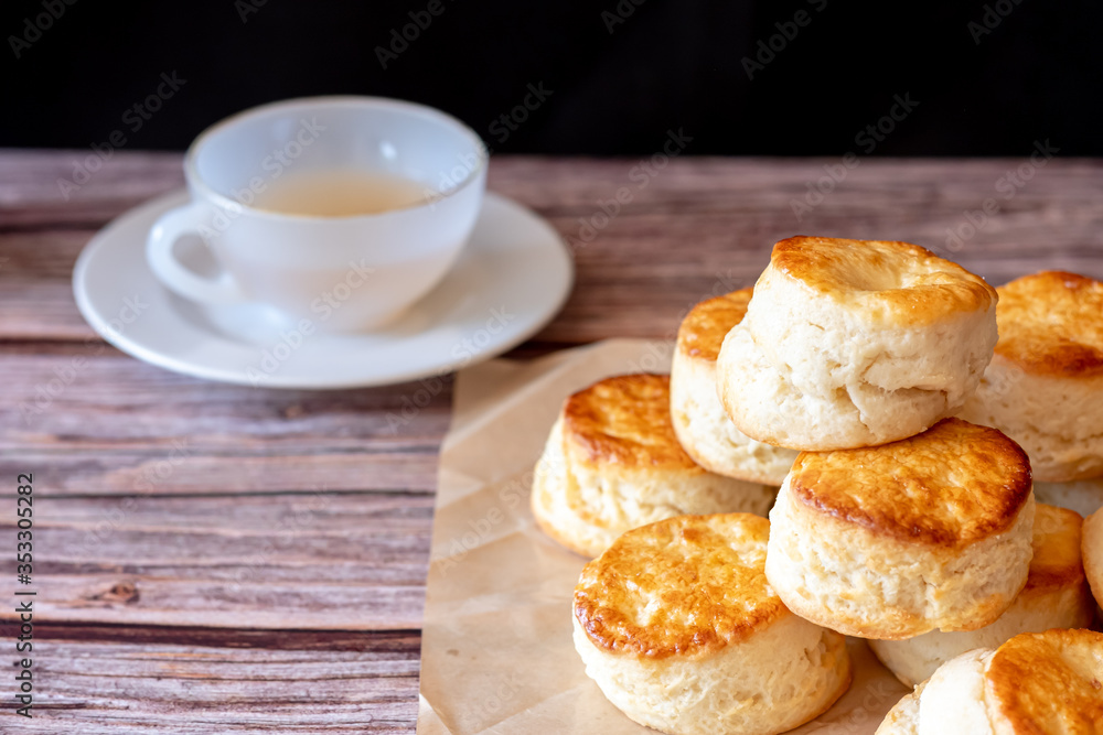 Close up group of fresh yummy tasty delicious Traditional British Scones and a cup of tea on wooden table black background.