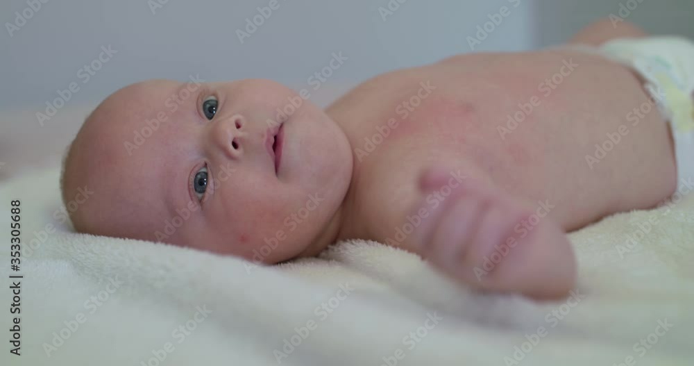 Funny portrait of newborn baby lying on bed and looking surprisely aside Funny portrait of newborn baby lying on bed and looking surprisely aside