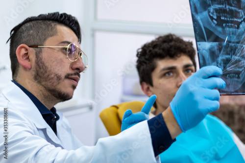 Male doctor showing an x-ray plate to his young male patient