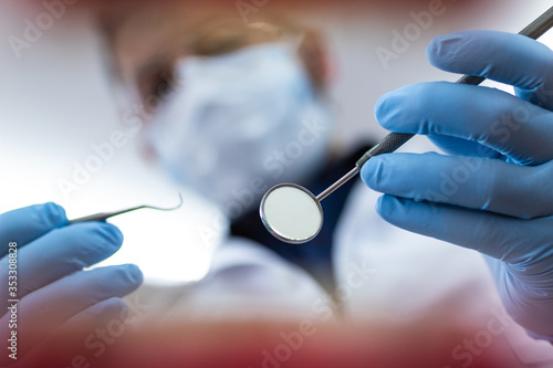 Male dentist holding a mouth mirror close to the camera