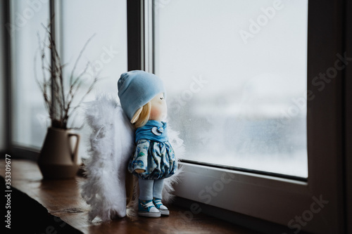 doll standing at the window, toy, baby cradle, girl, play, made with your own hands, creativity, windowsill, winter in the yard, glass, angel, white wings, blonde, stands on the Board interior item
