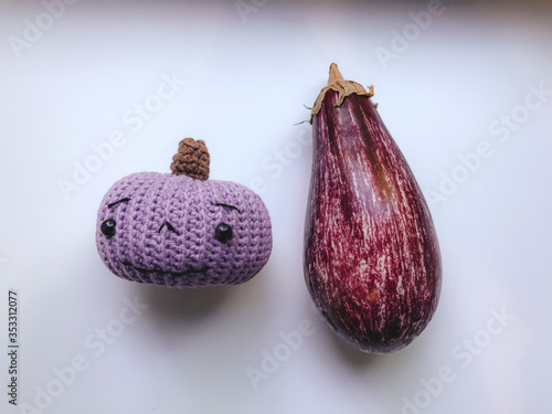 Knitted pumpkin and fresh eggplant on a white background, vegetarian product top view