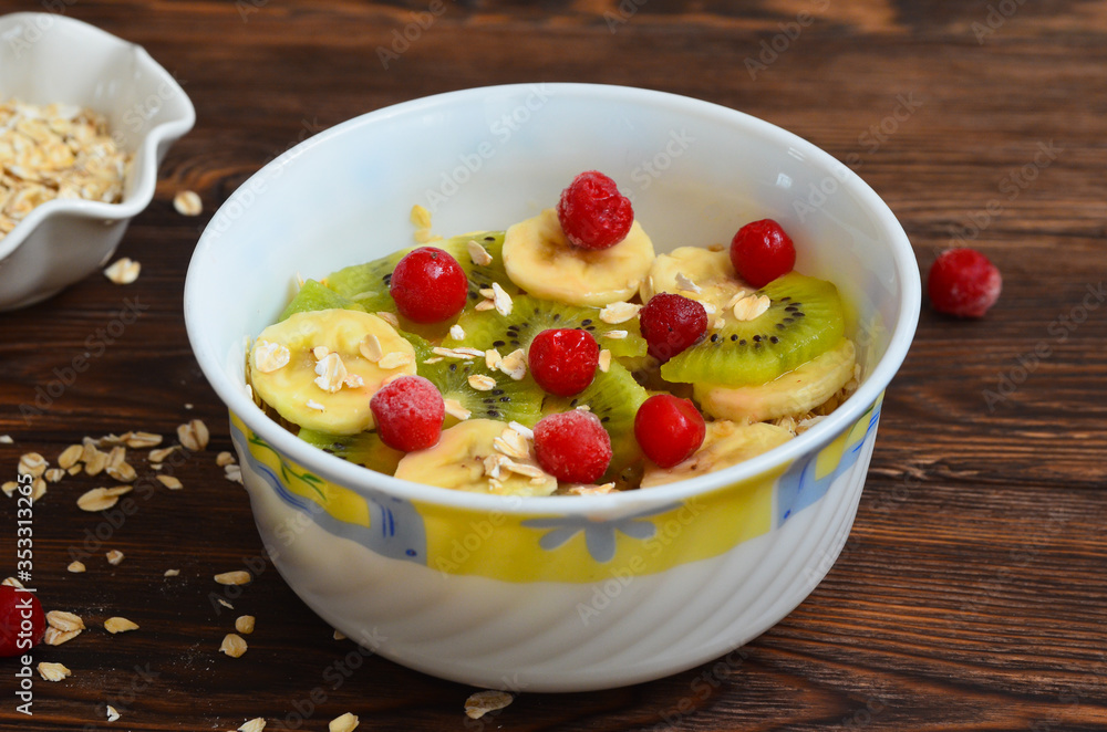 A rich and healthy breakfast. Oatmeal porridge with fruit and berries with kiwi banana and cherry. Diet concept. Natural and eco friendly food on a wooden table A rich and healthy breakfast. Oatmeal porridge with fruit and berries with kiwi banana and cherry. Diet concept. Natural and eco friendly food on a wooden table