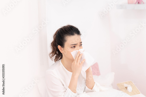 Sick woman with headache sitting under the blanket. Sick woman with seasonal infections, flu, allergy lying in bed