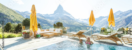 Mother and daughter swimming in outdoor swimming pool in the mountains photo