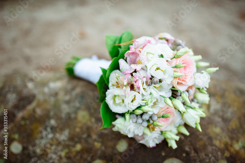 The bride’s wedding bouquet lies on a large stone.